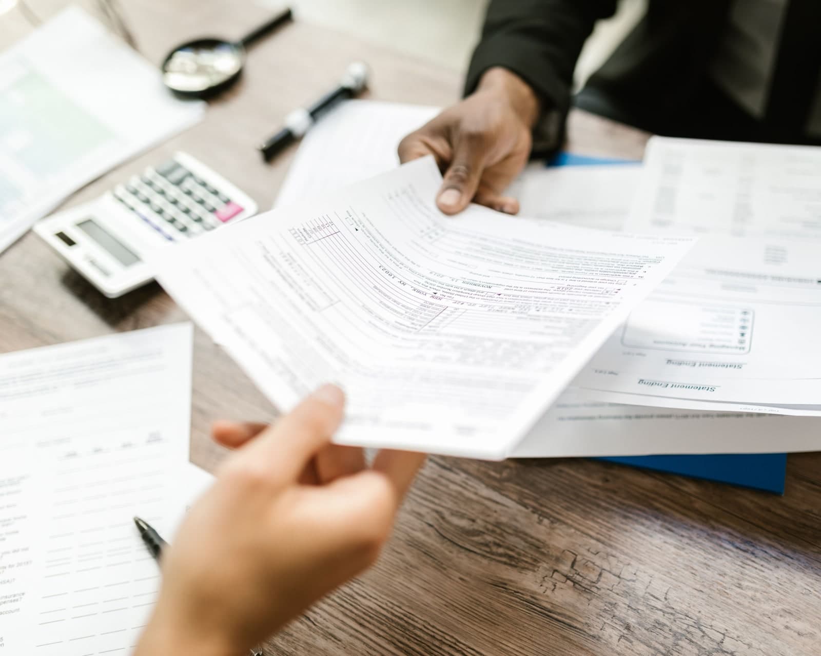 Two professionals exchanging financial records during a control review.