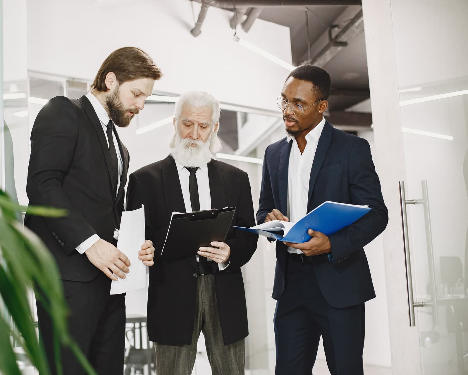 Three executives reviewing prudential documents together in a bright meeting space.
